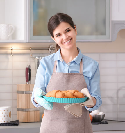 women baker holding a tray of baked goods