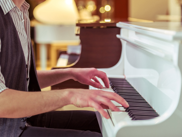 man playing a piano with a focus on hands and keys