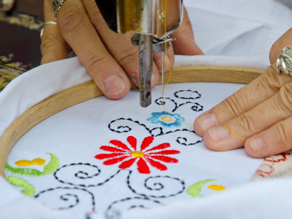 person embroidering a flower design