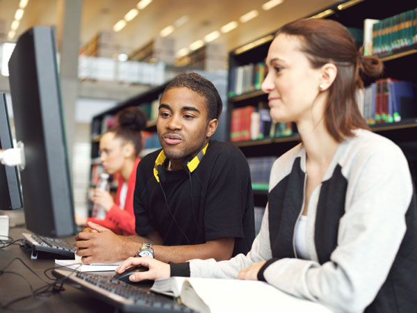 women in a library tutoring a student